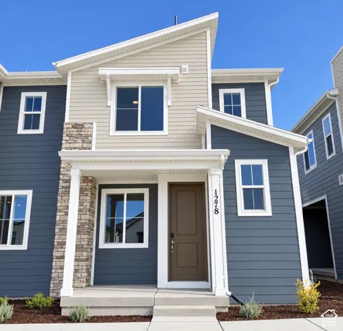 Modern exterior featuring a combination of horizontal lap siding and decorative stone veneer, a covered front entryway with white architectural pillars, and multi-pane windows