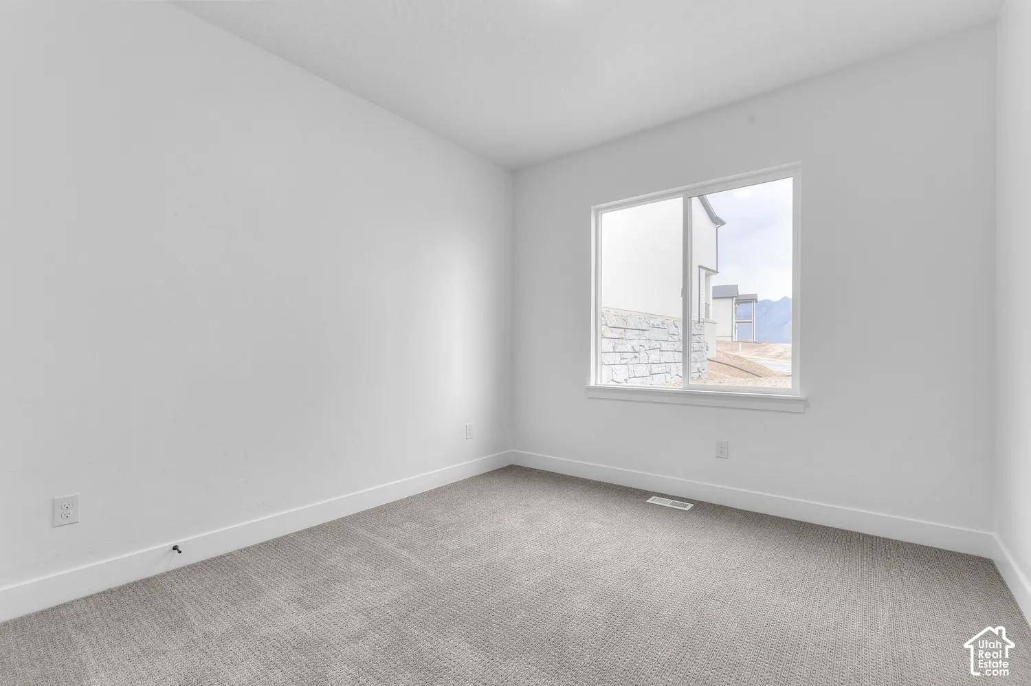Neutral-toned carpeted flooring, white wall finishes, and a single sliding window