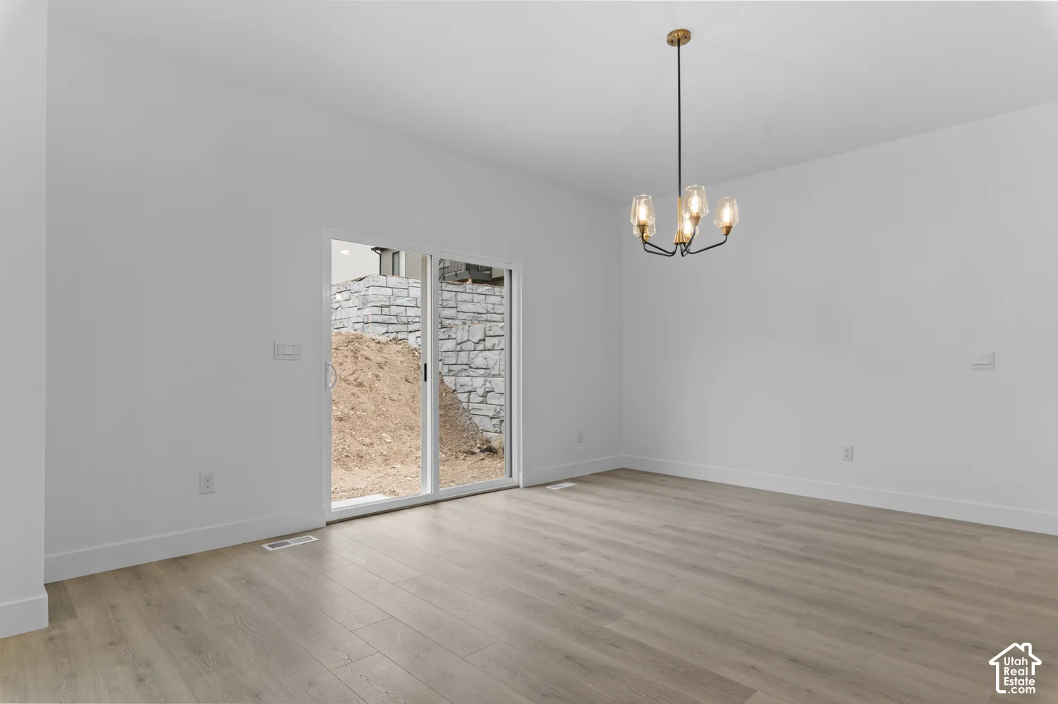Interior space featuring wood-finish flooring, a contemporary multi-light chandelier, and sliding glass doors