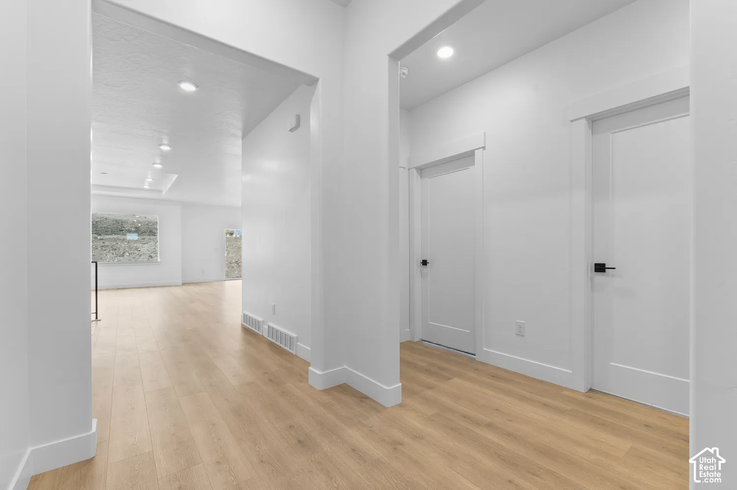 Interior hallway featuring wood-finish flooring, recessed lighting, and crisp white interior doors with matte black hardware