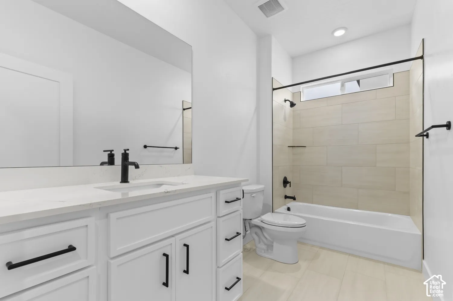 White vanity with a stone countertop, under-mount sink, matte black faucet, and horizontal light-toned tile surround in the shower enclosure