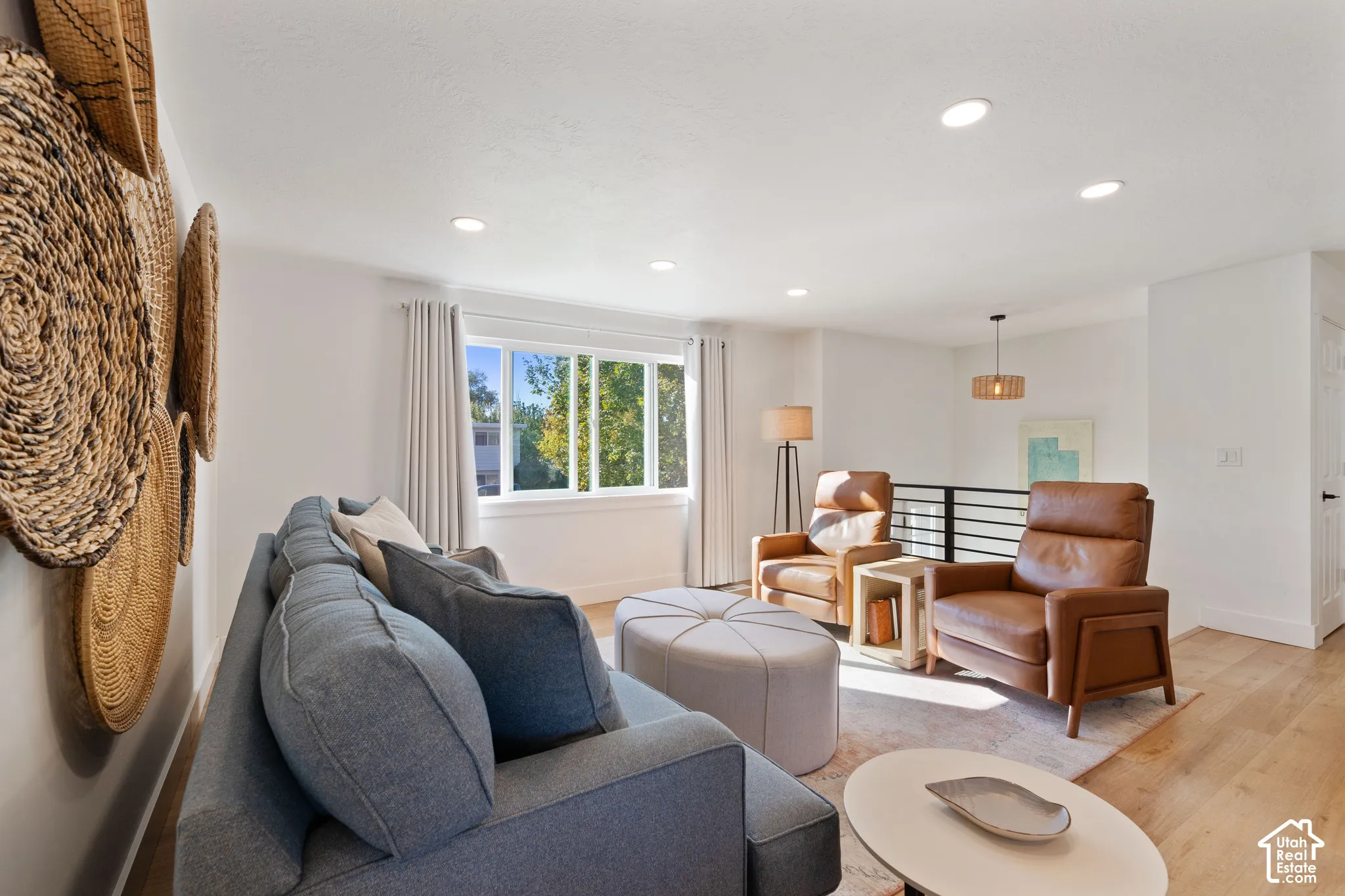 Living area featuring wood-finish flooring, recessed lighting, a horizontal sliding window, and a metal horizontal-slat staircase railing