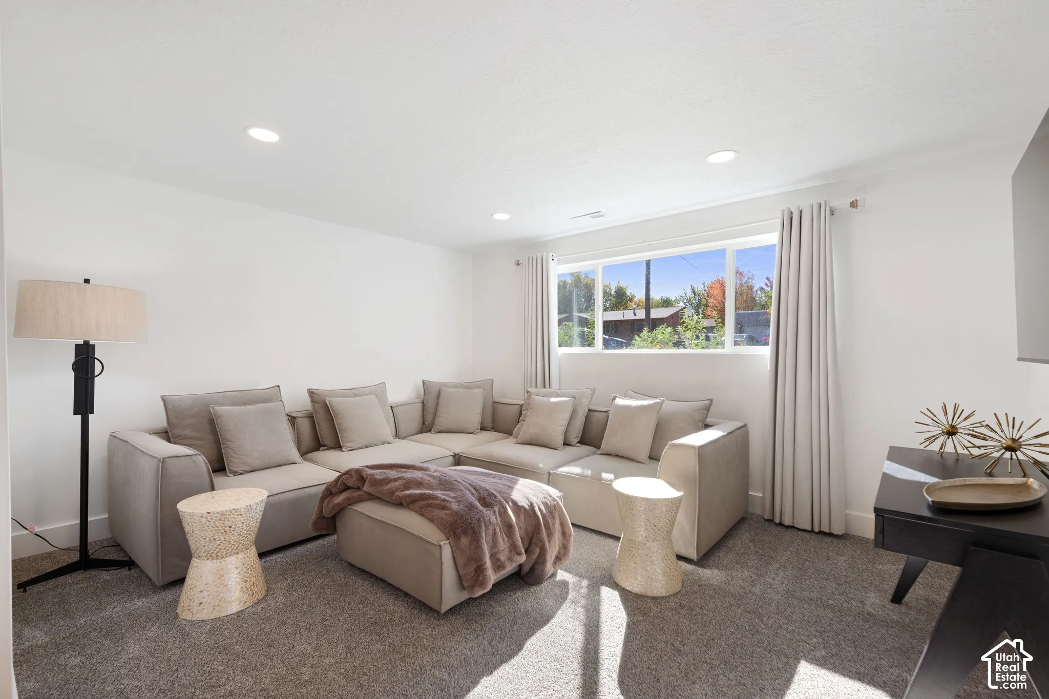 Neutral-toned interior featuring plush carpeting, recessed lighting, and a large window