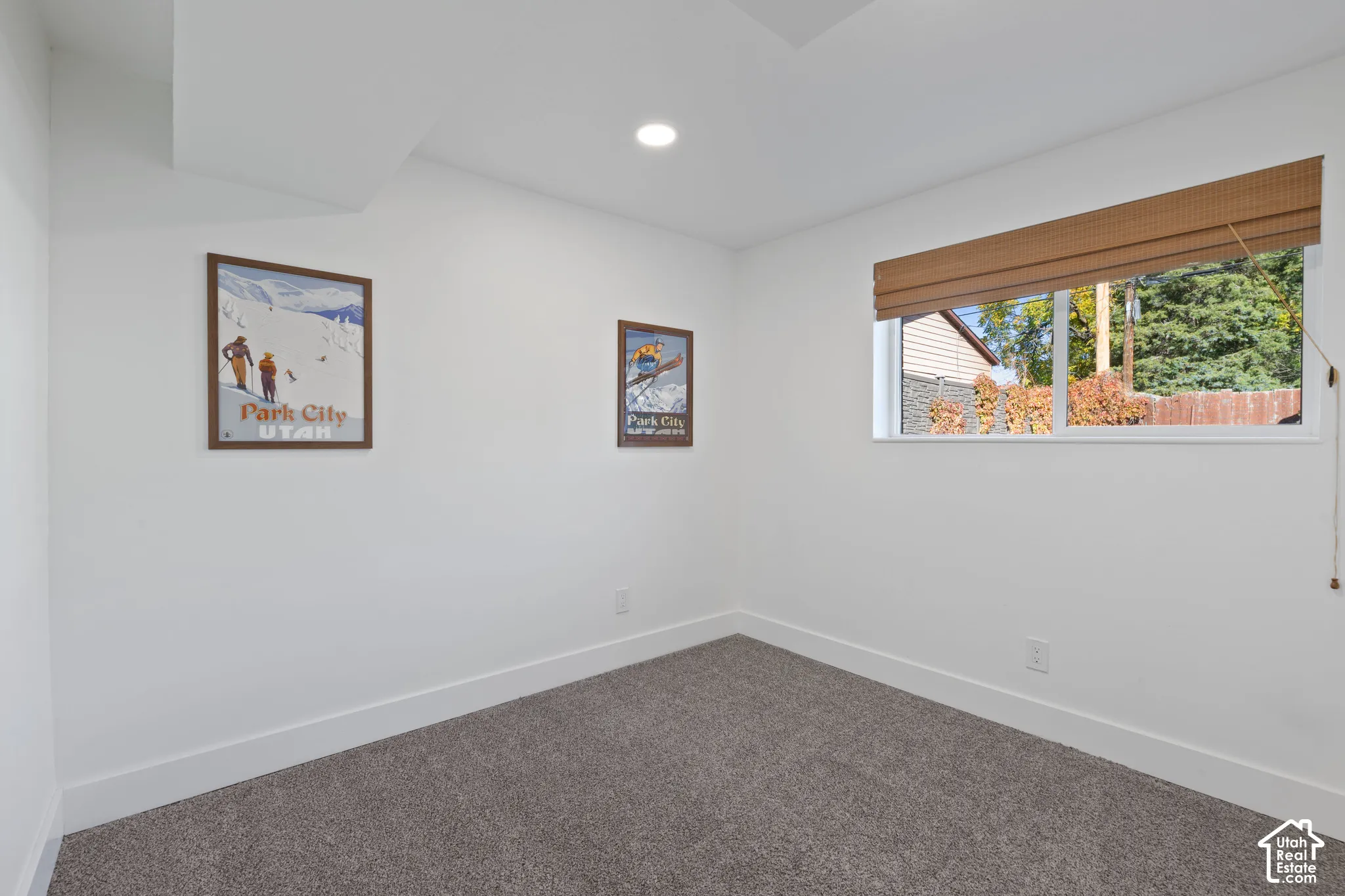 Neutral-toned carpeting, recessed ceiling lighting, and a window featuring a natural woven shade