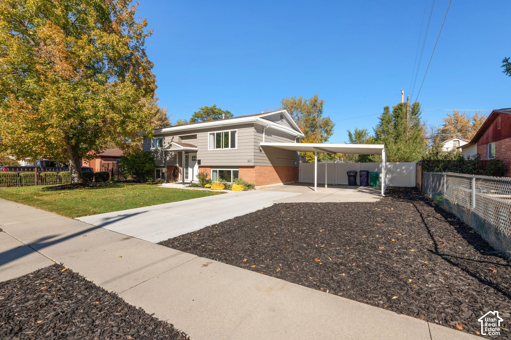 Split-level exterior featuring a brick and horizontal siding facade, a covered carport, and a concrete driveway