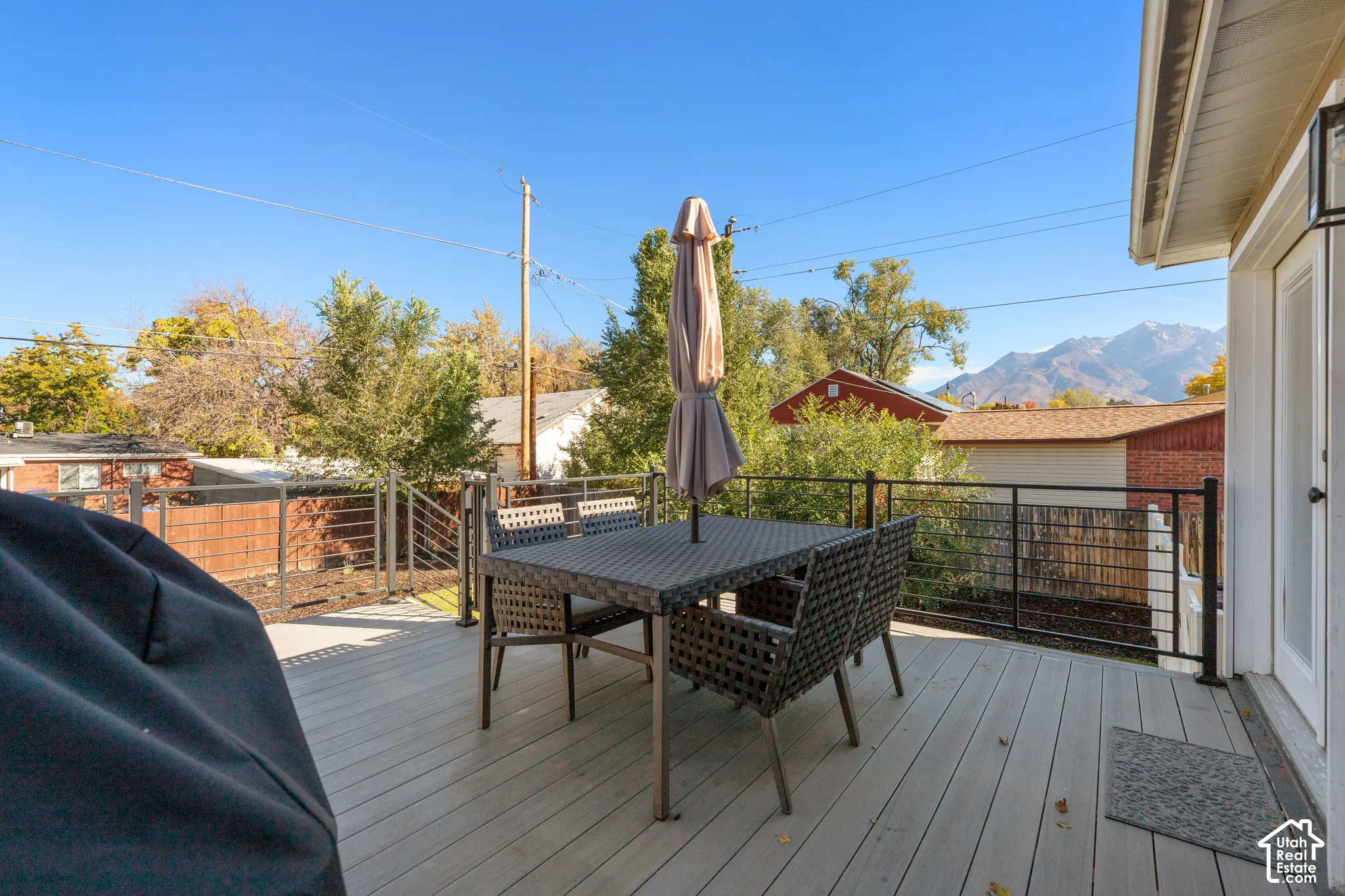 Elevated deck featuring composite decking and a black metal railing with horizontal wire infill, set against a backdrop of mountain scenery