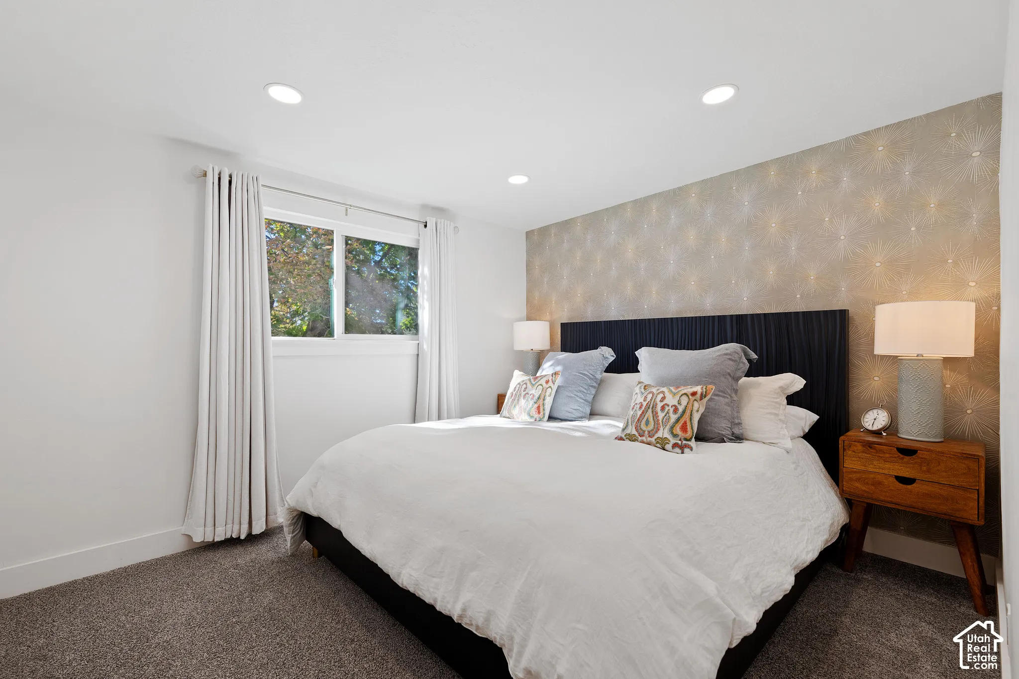 Bedroom featuring recessed lighting, a neutral patterned accent wall, and wall-to-wall carpeting