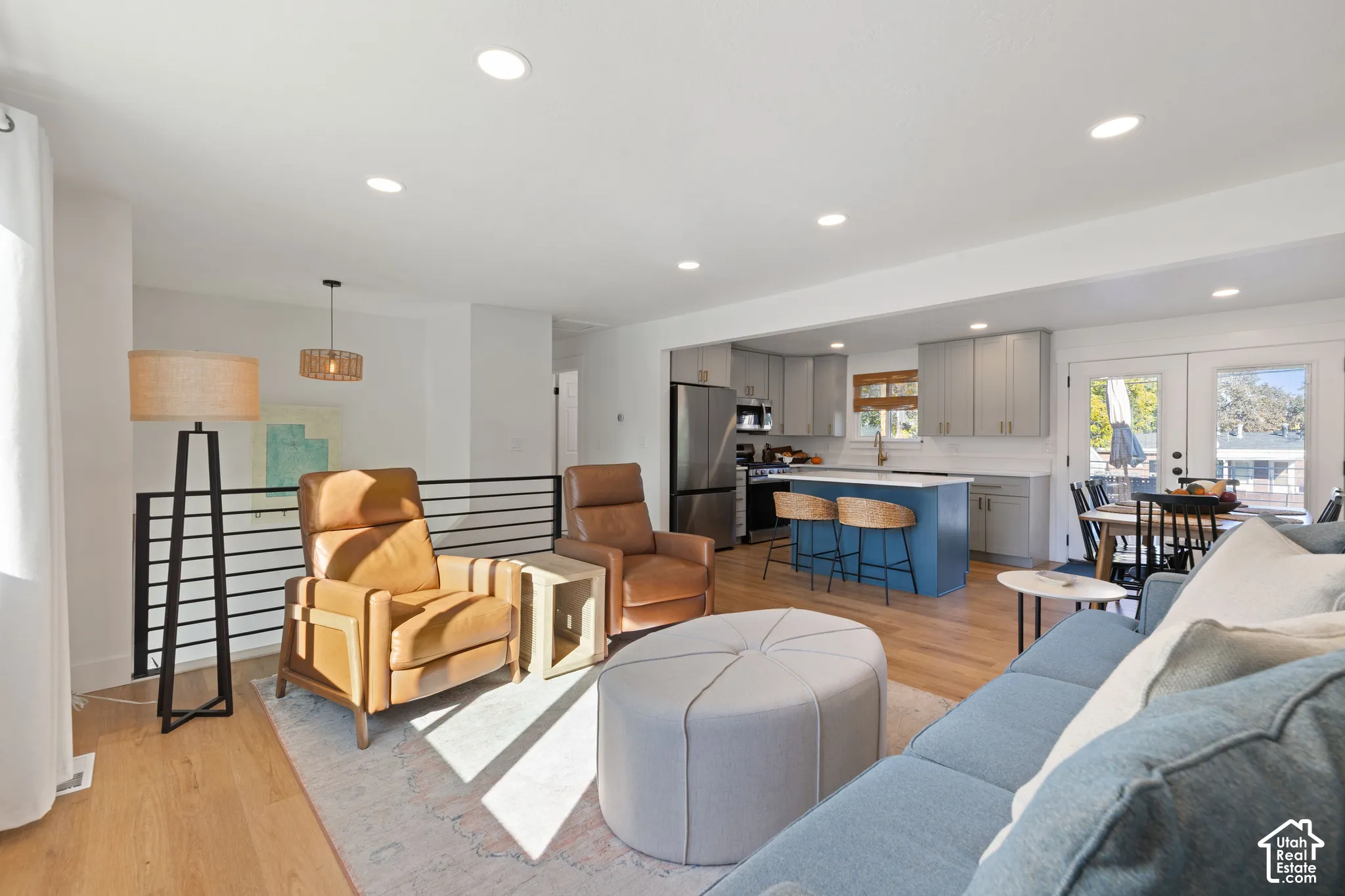 Open-concept living space featuring wood-finish flooring, recessed lighting, and a modern kitchen island with a contrasting finish