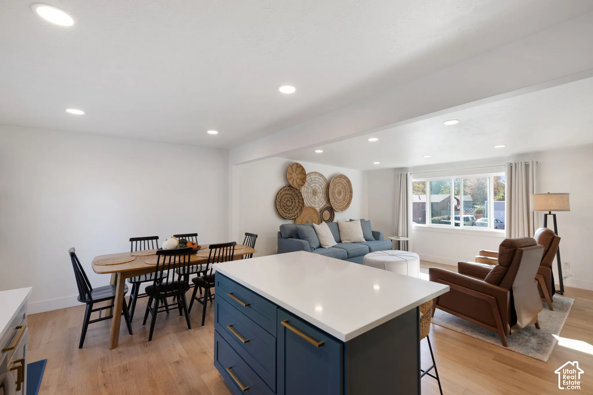 Kitchen island featuring navy cabinetry, stone countertop, and gold-tone hardware, complemented by wood-finish flooring and recessed lighting
