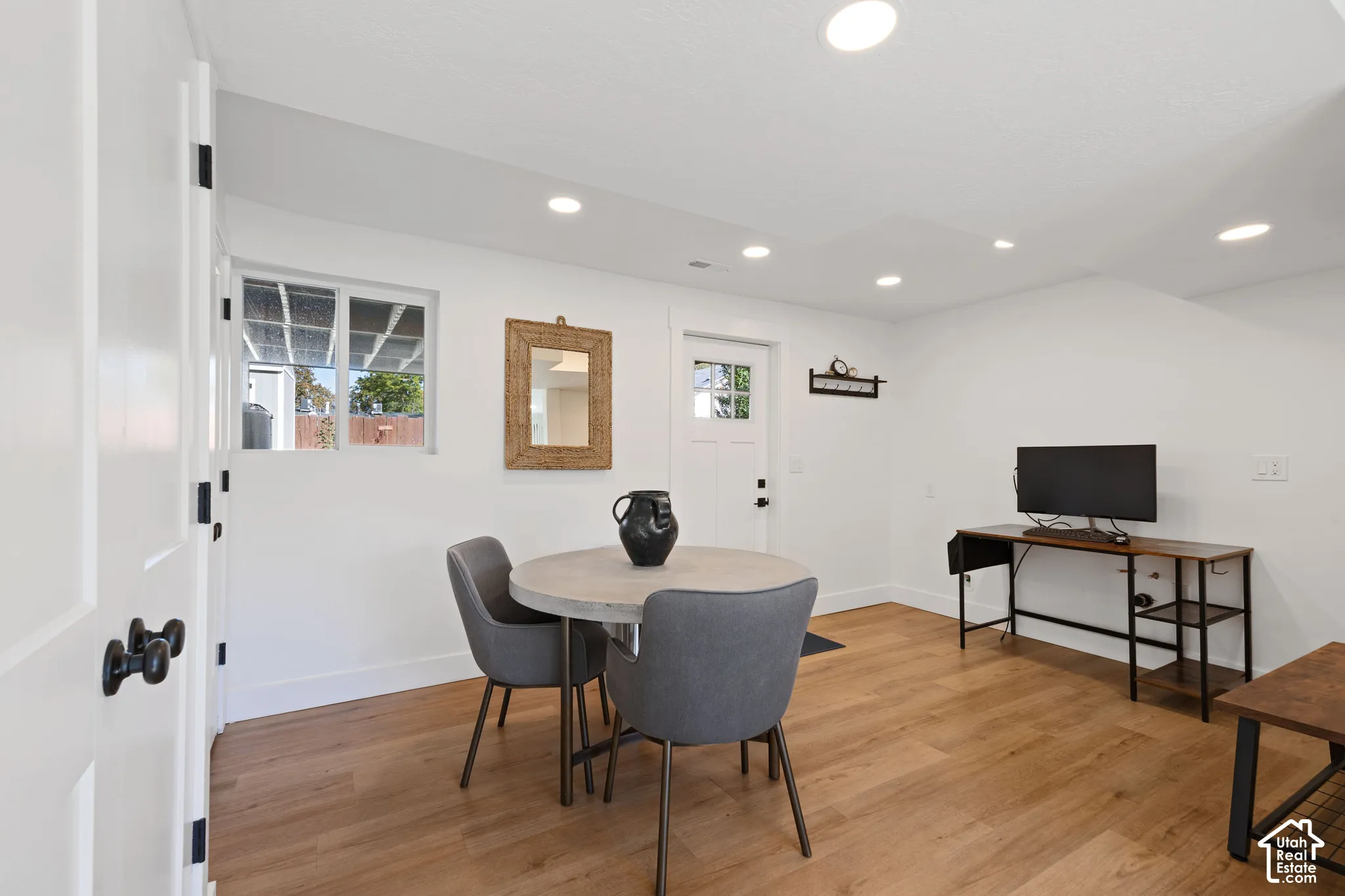 Wood-finish flooring, recessed lighting, white interior walls, and a single-pane exterior door