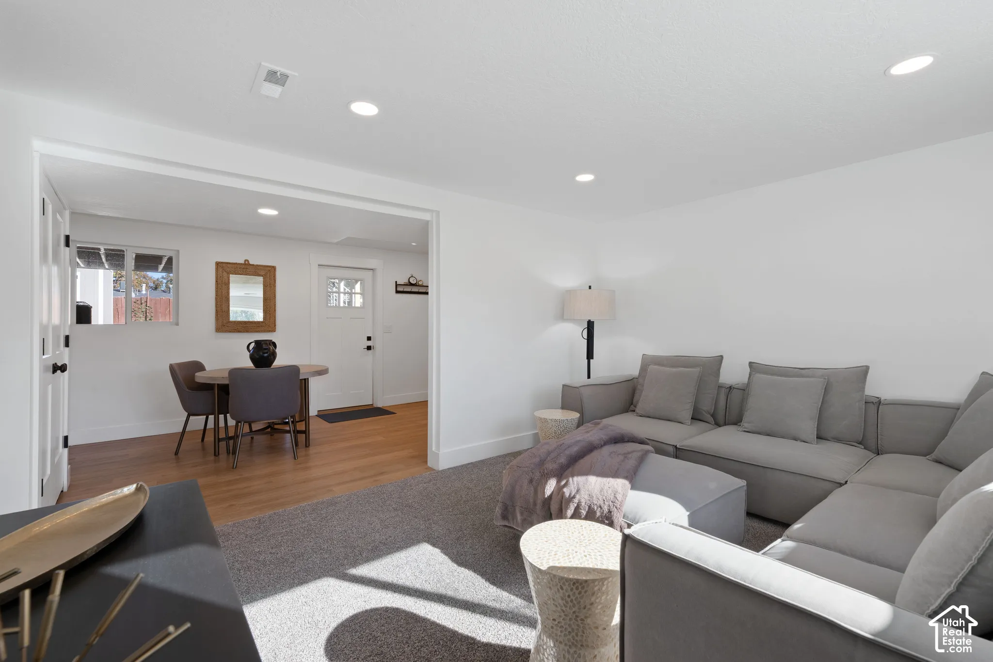Interior space featuring neutral-toned carpeting, wood-finish flooring, recessed lighting, and a multi-pane glass entry door