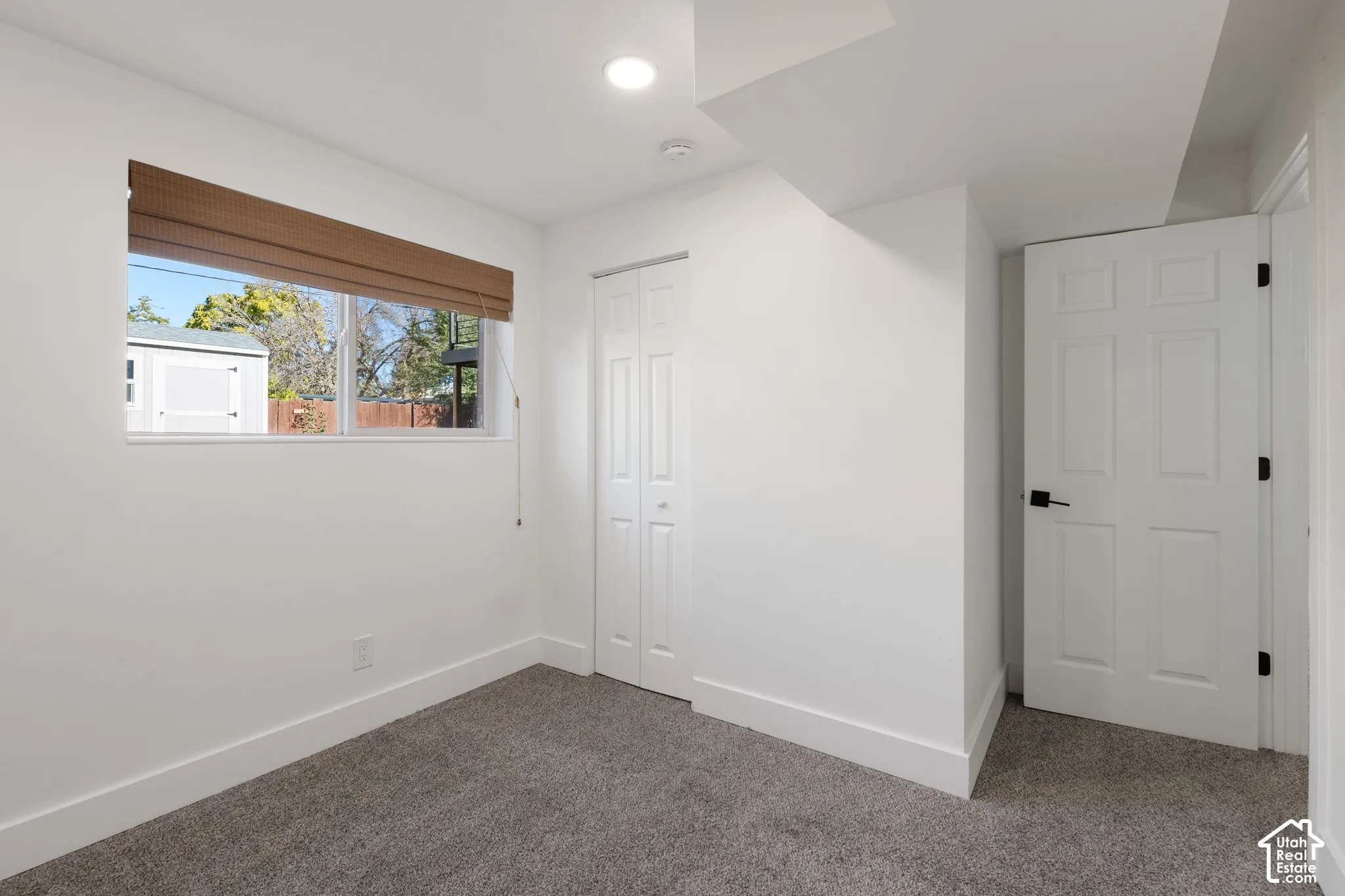 Interior space featuring neutral carpeting, recessed ceiling lighting, a bi-fold closet, and a six-panel door with matte black hardware