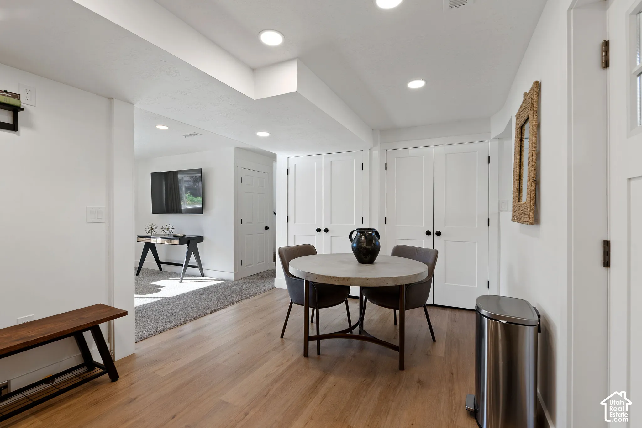 Interior space featuring wood-finish flooring, recessed lighting, and double-door storage closets with matte black hardware
