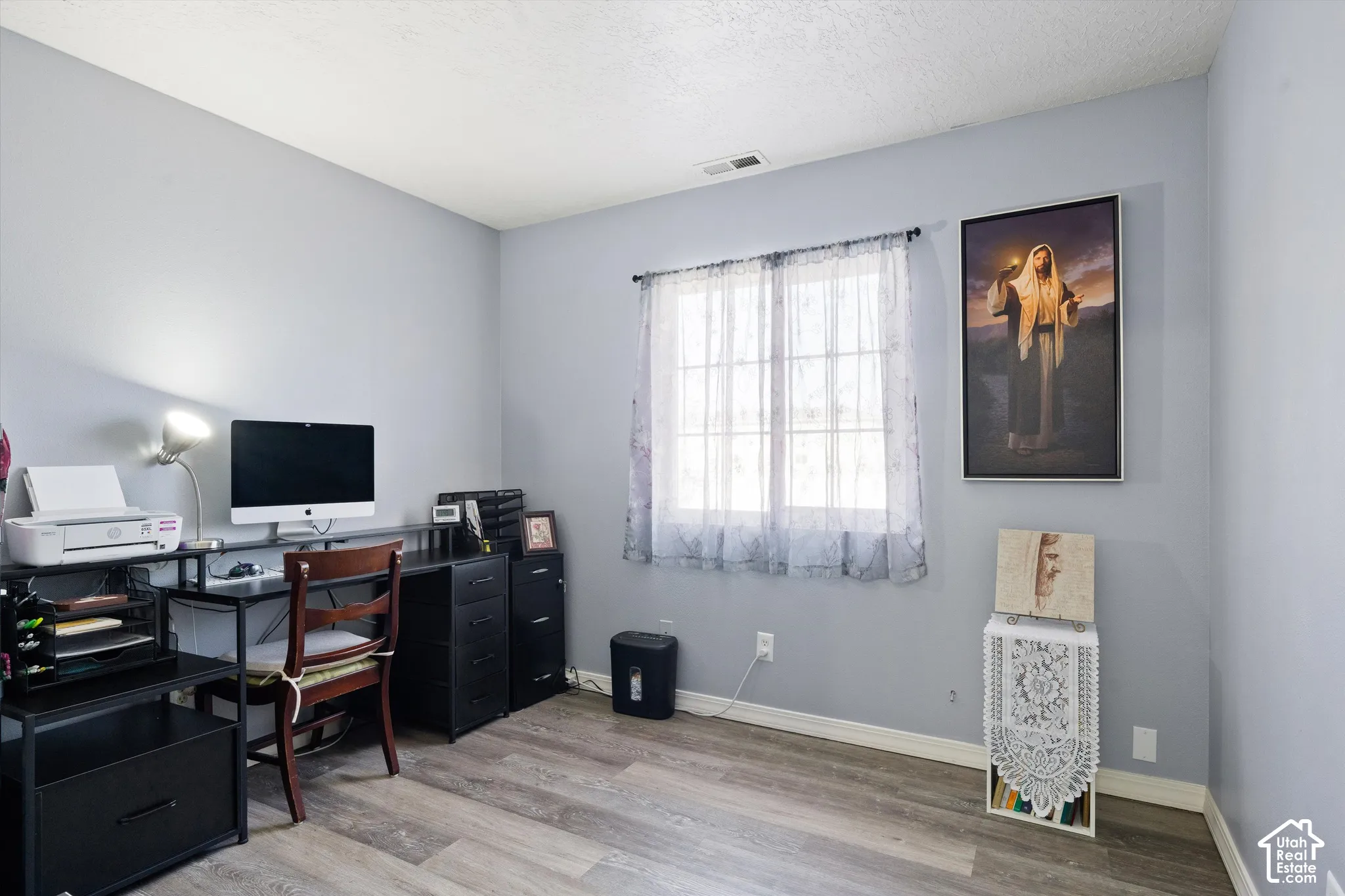Neutral-toned interior space featuring wood-finish flooring and a dual-pane window with a grid pattern