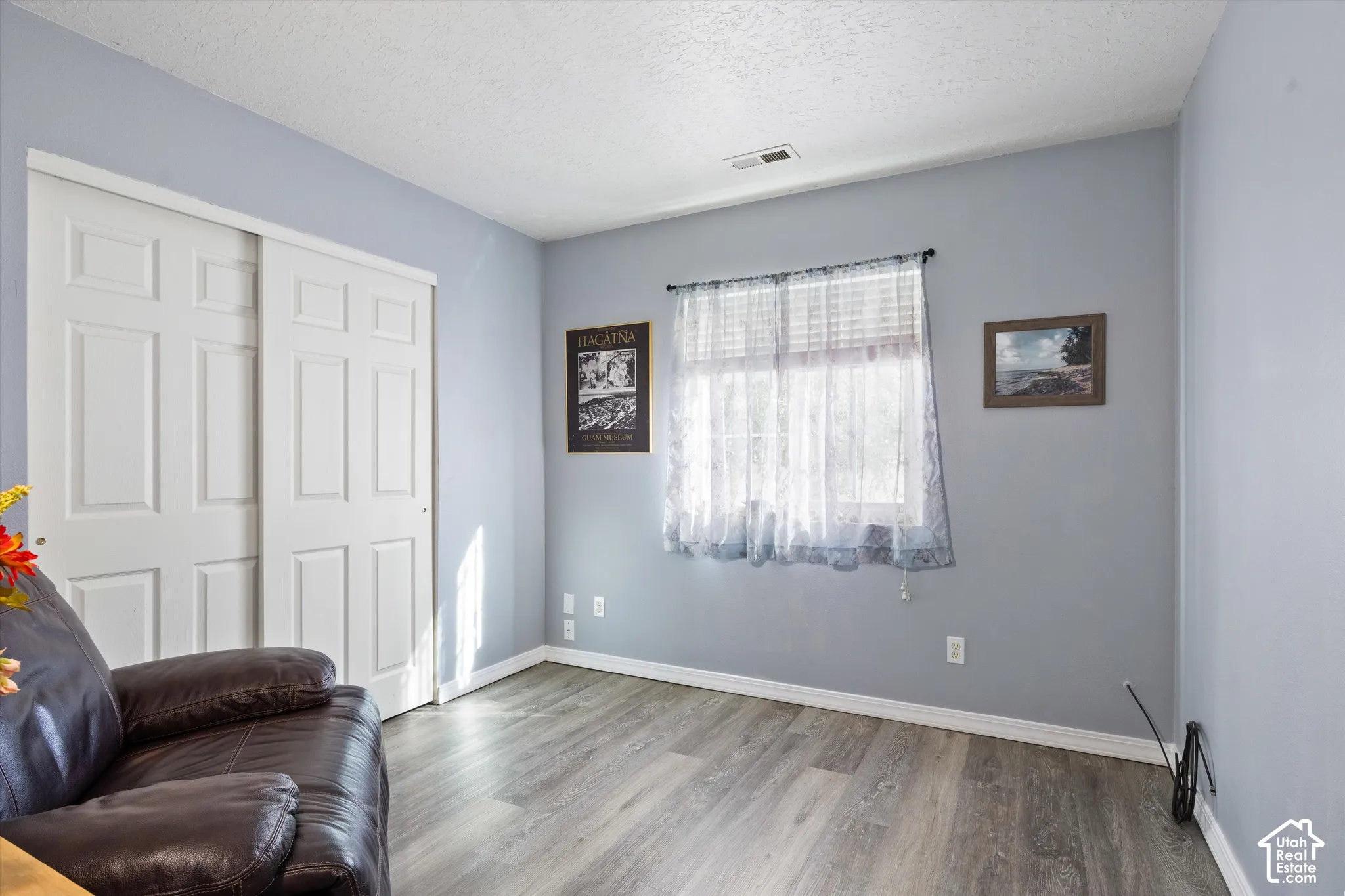 Room featuring wood-finish flooring, light grey walls, and a sliding-door closet