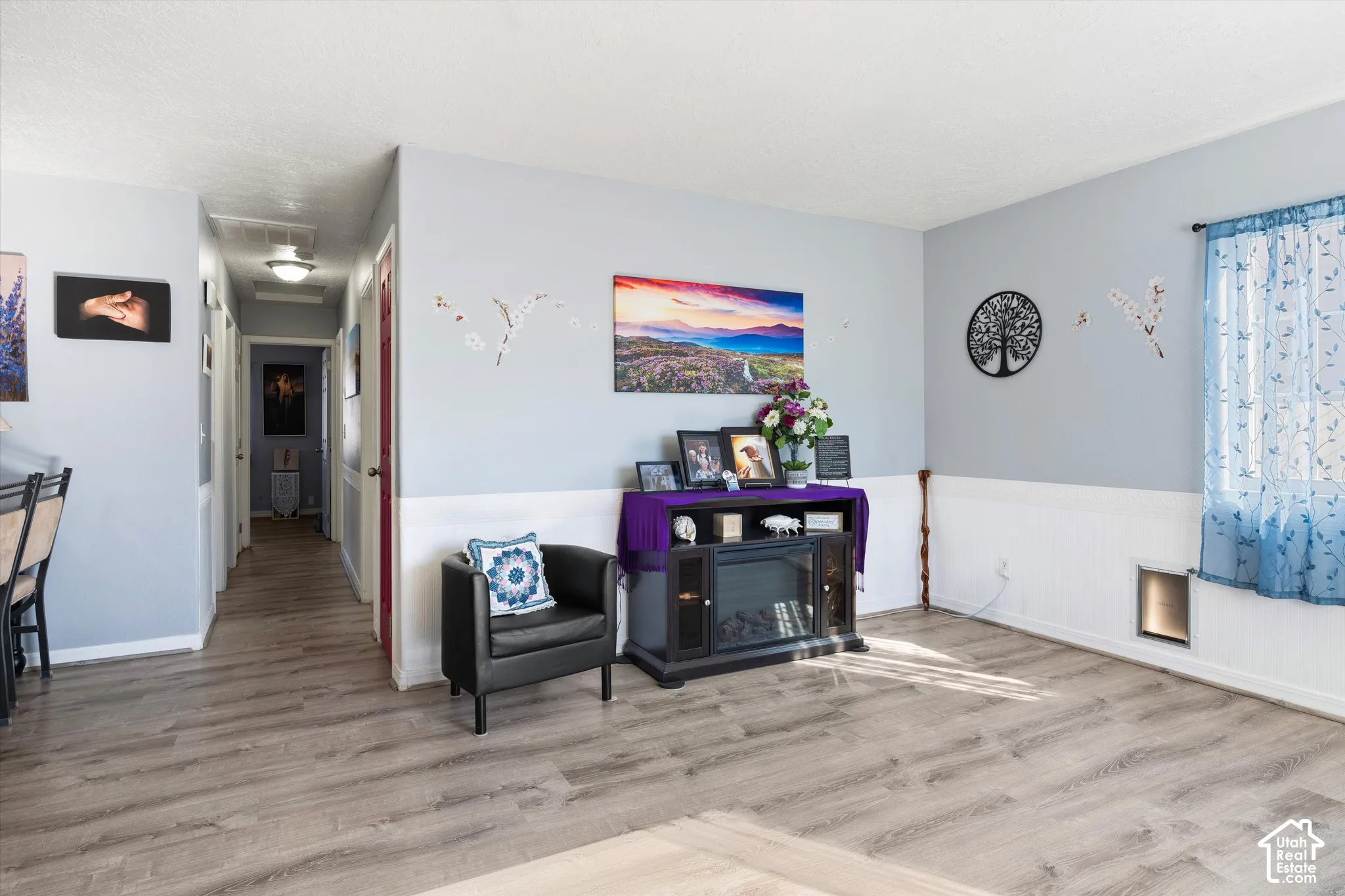 Wood-finish flooring, white wainscoting, and neutral wall paint