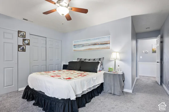 Room featuring carpeted flooring, a multi-blade ceiling fan with integrated lighting, and dual-panel closet doors