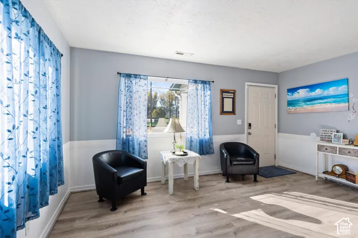 Neutral-toned walls featuring lower-wall wainscoting and wood-finish flooring