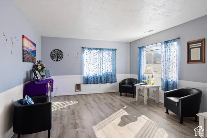 Living area featuring wood-finish flooring, wainscoting, and large windows