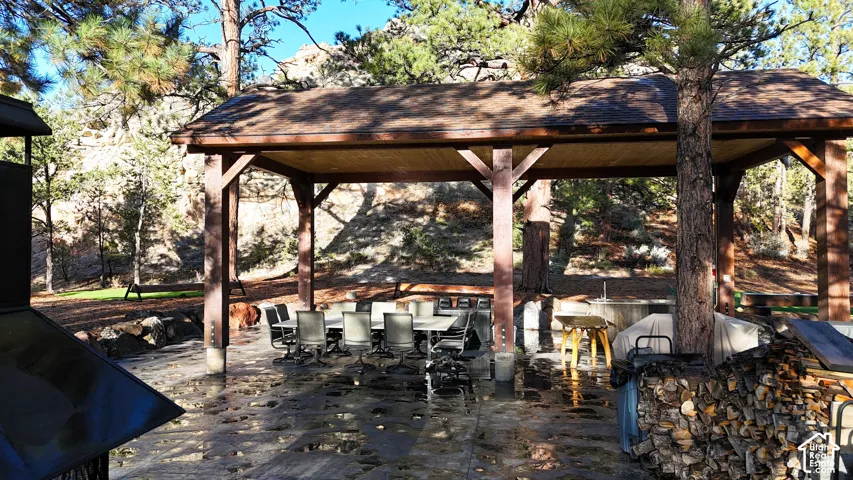 Covered outdoor pavilion with heavy timber framing, tongue-and-groove wood ceiling, and expansive stone paver patio