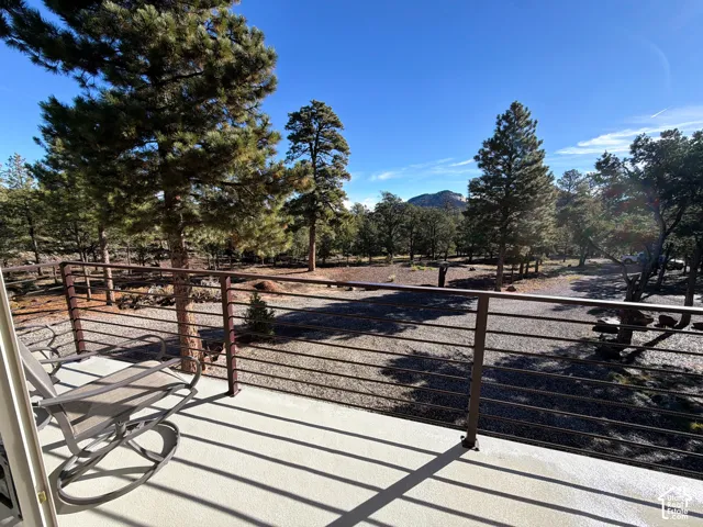 Elevated balcony featuring a metal horizontal railing, concrete flooring, and mountainous backdrop
