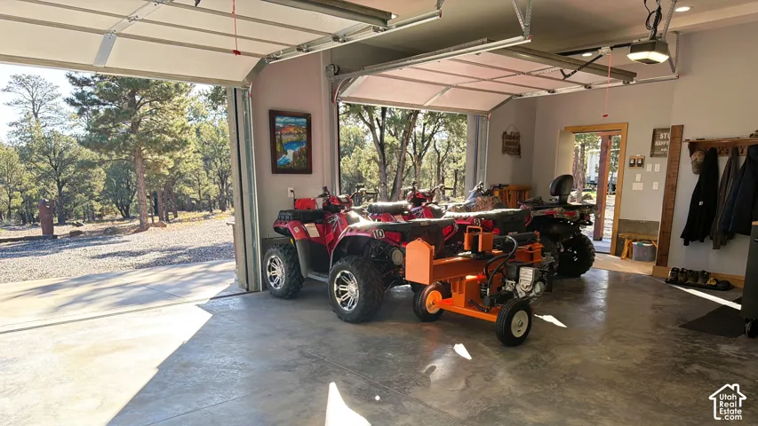 Spacious two-car garage featuring finished concrete flooring, dual automatic overhead doors, recessed lighting, and wooden door trim