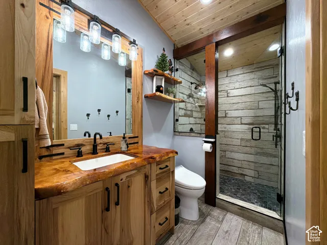 Bathroom featuring custom wood cabinetry with a live-edge countertop, an integrated rectangular vessel sink, matte black hardware, wood-plank ceiling treatment, and a walk-in shower with textured tile surround and glass enclosure