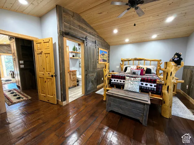 Vaulted tongue-and-groove wood ceiling, wide-plank wood-finish flooring, sliding barn door with hardware, and natural wood-toned trim