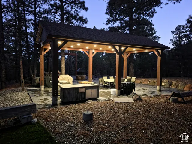 Covered timber-frame pavilion featuring a stone patio, recessed ceiling lighting, and a built-in outdoor kitchen with a sink