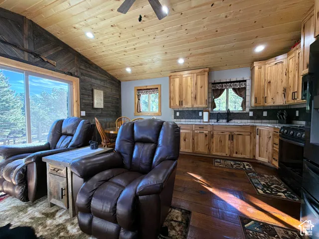 Vaulted wood-plank ceiling, natural wood cabinetry, wood-finish flooring, and dark stained shiplap accent wall
