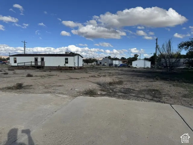 Expansive lot featuring a concrete parking pad, a detached storage structure, and mountain topography in the distance
