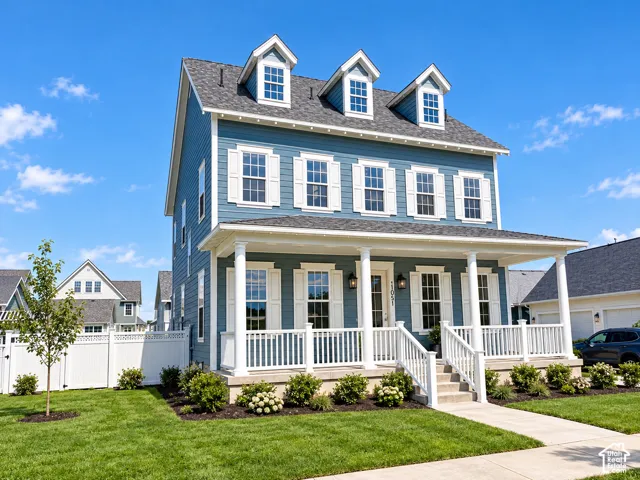 Three-story residence featuring blue lap siding, white shutters, a full-length covered front porch with classic columns, and three roof dormers
