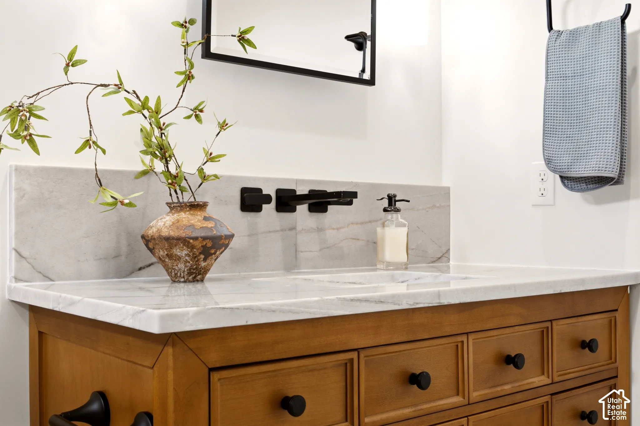 Stained Wood vanity featuring a statement wall mounted Kohler faucet, integrated Denali Quartzite countertop and backsplash.