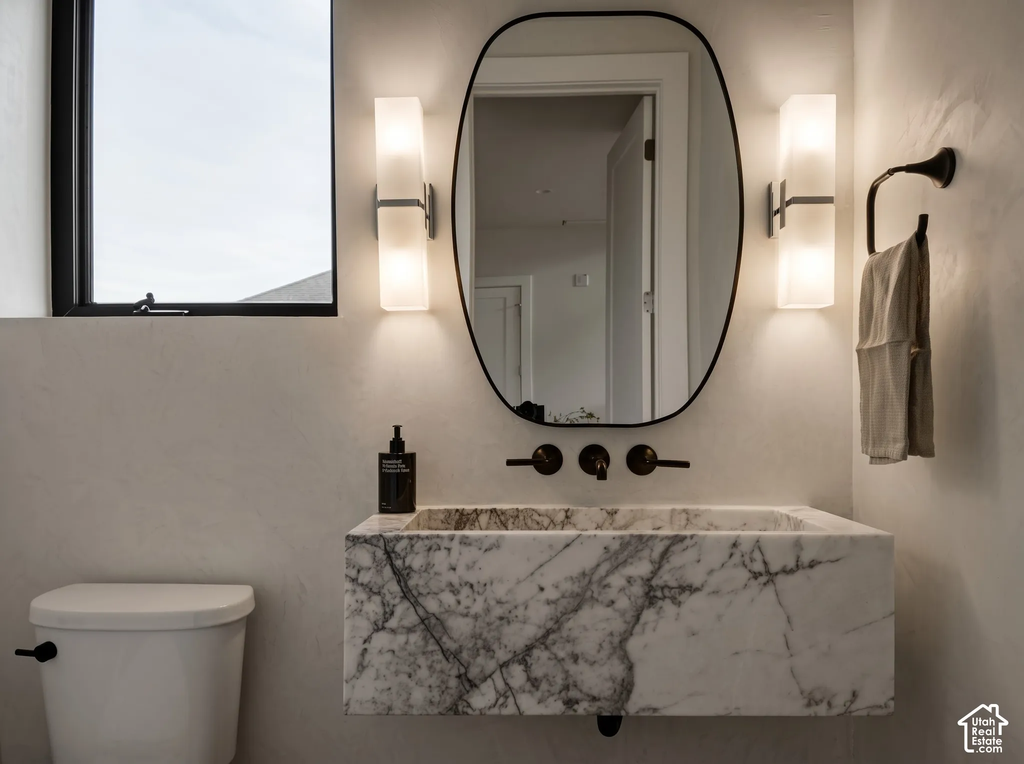Main level Powder Bathroom featuring a hand cut, solid, Lilac Marble floating vessel sink, Portola Roman Clay, dual Kohler Honesty wall-mounted sconces, and Kohler Tone matte finish wall-mounted faucet
