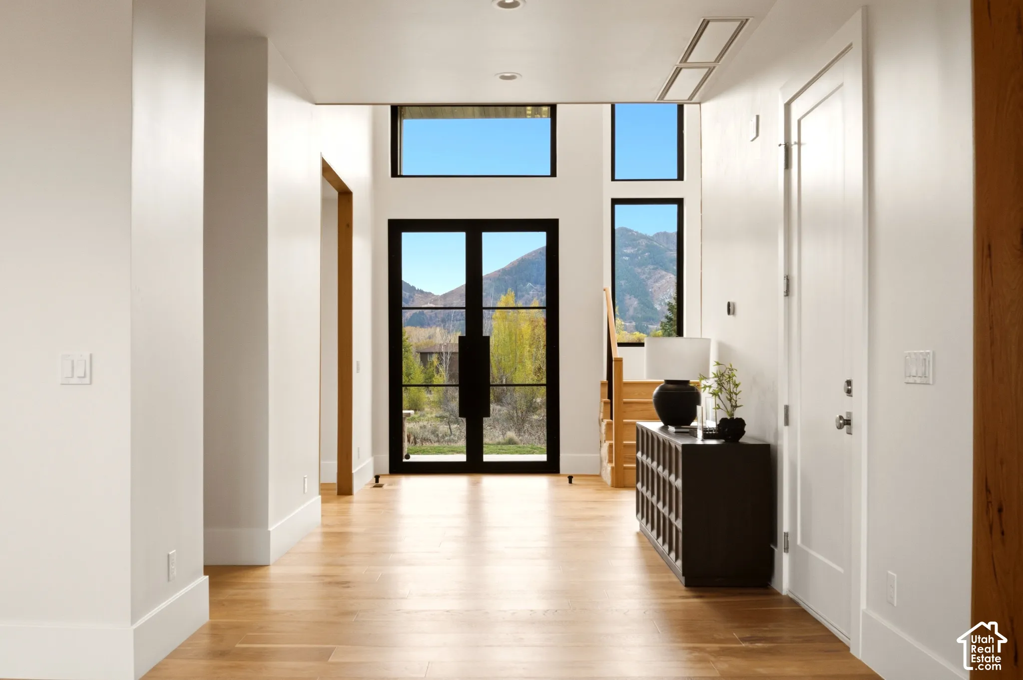 Double-height entry featuring engineered hardwood flooring, 9' iron glass double doors, floor-to-ceiling windows, and mountain scenery