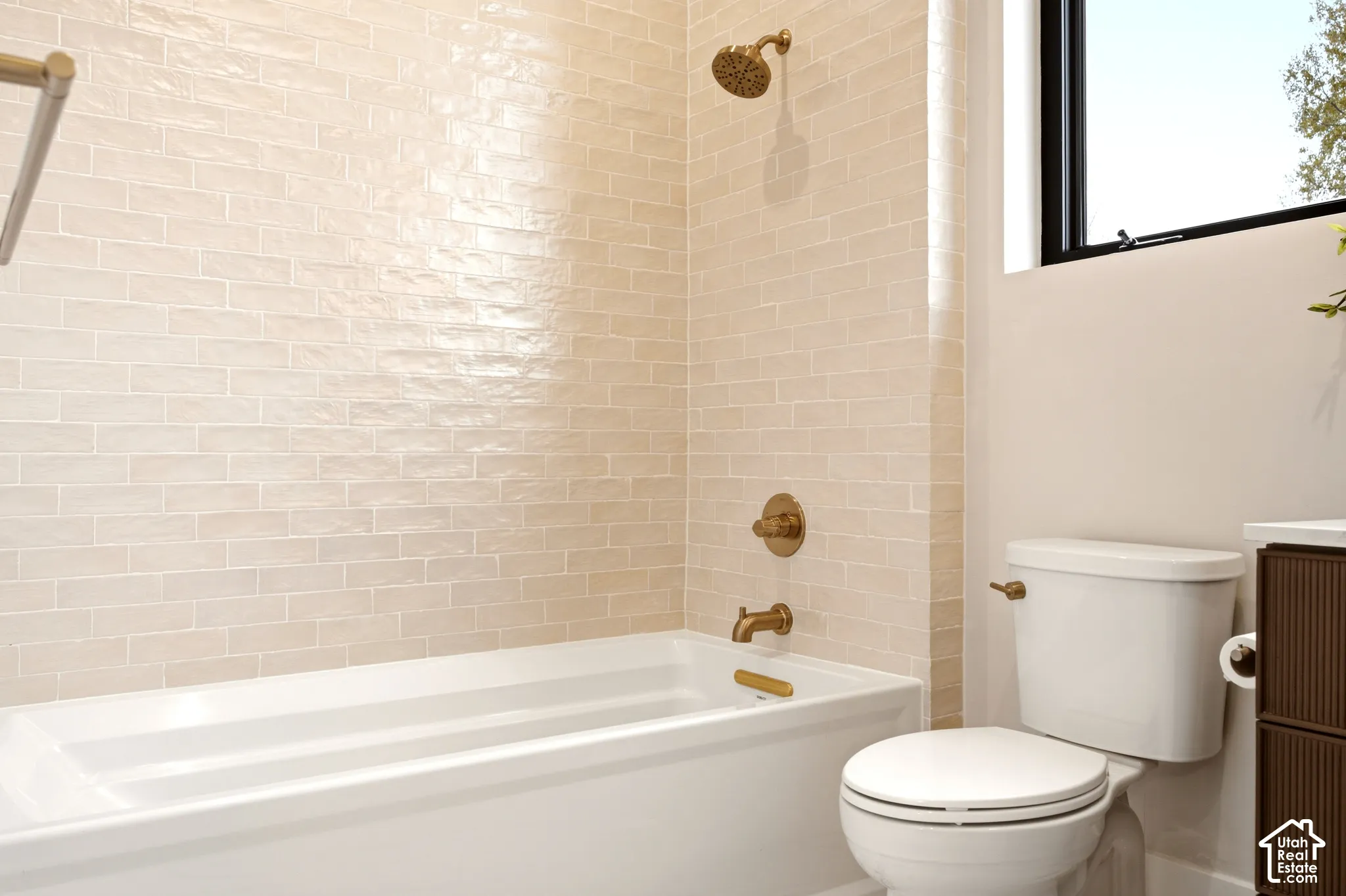 Main Level En-Suite Bathroom featuring a gloss-finish subway tile tub surround, brass fixtures, and extra deep soaking tub