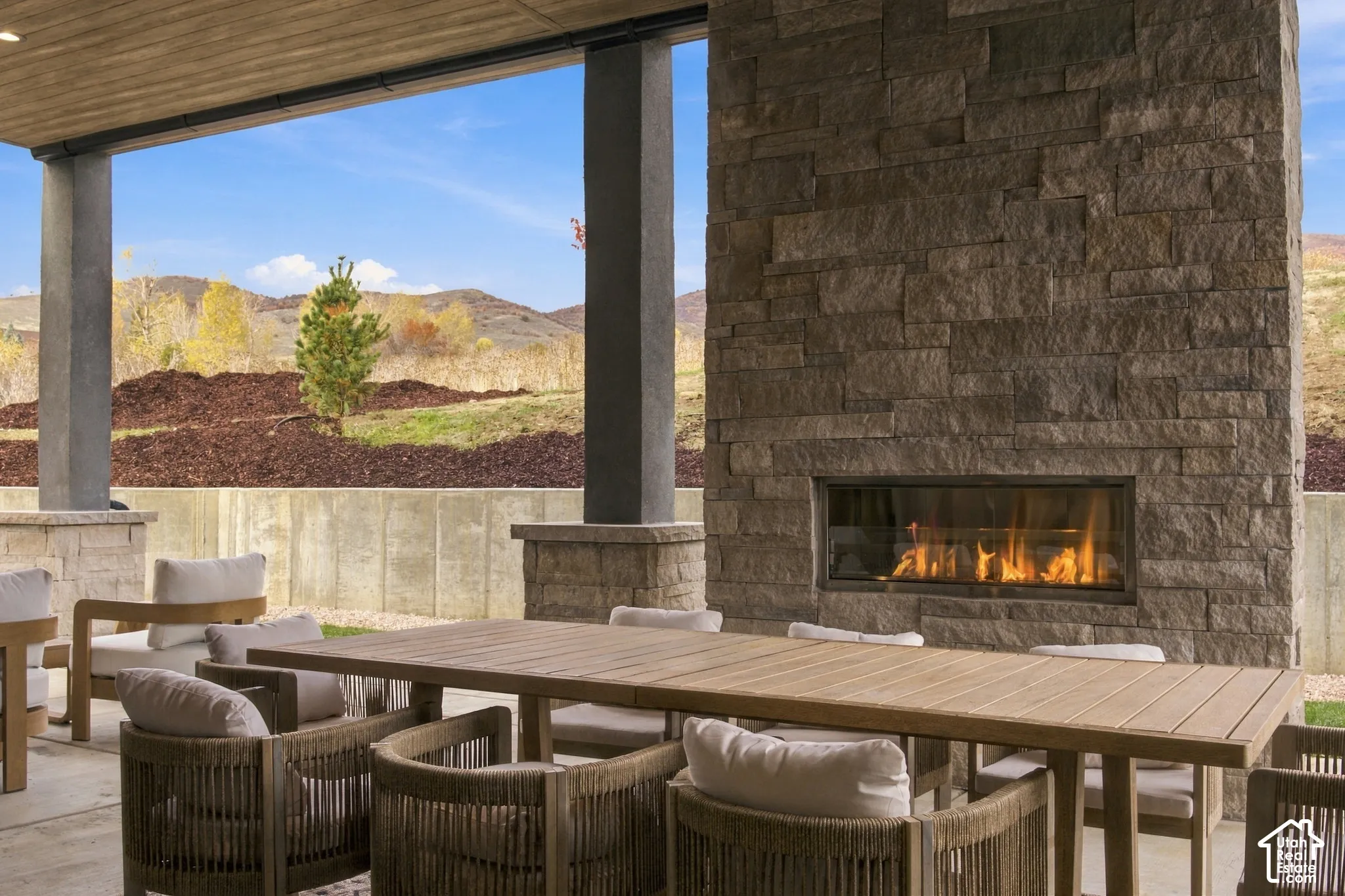 Covered patio featuring dry-stacked  natural limestone fireplace, Cham Clad wood-finish ceiling, structural stone pillars, and beautifulmountain scenery