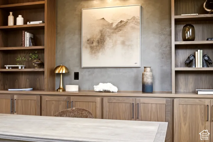Custom walnut wood cabinetry featuring recessed-panel doors, open shelving, integrated lighting, and a roman clay finish accent wall