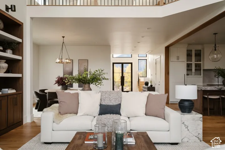 View through the 2-story great room capturing the natural light moving through the home. White oak accents, and kitchen visible