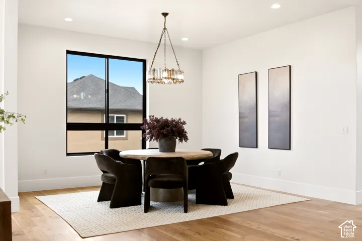 Dining space featuring Engineered Hardwood flooring, recessed lighting, a statement Arhaus metal chandelier, and a large black-framed window