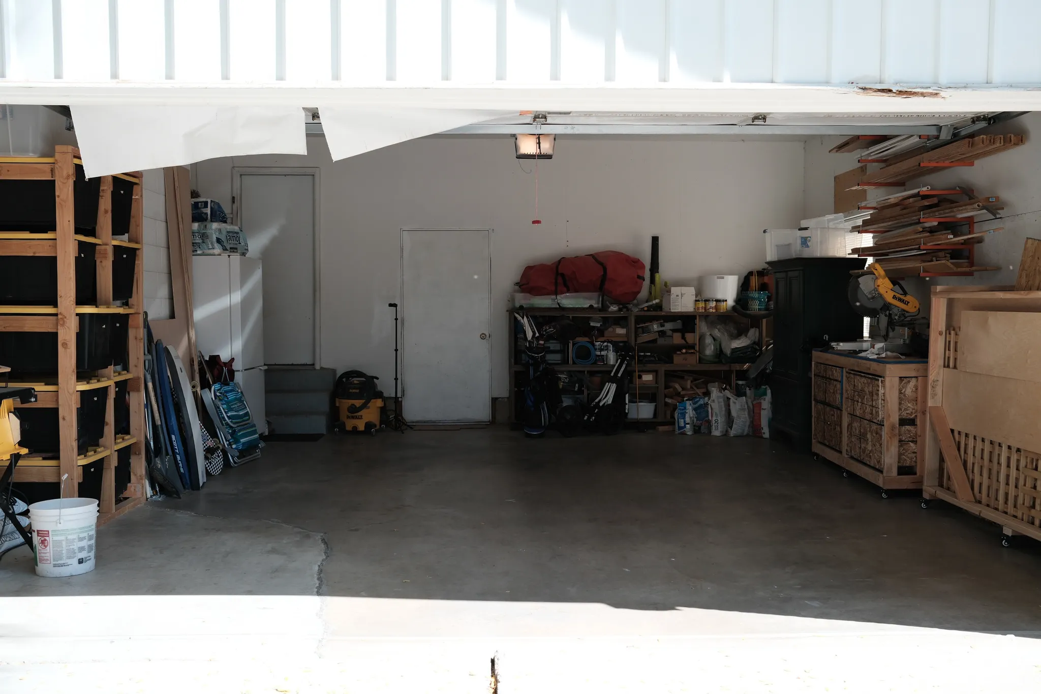 Attached garage featuring concrete flooring, wall-mounted shelving, and two pedestrian access doors