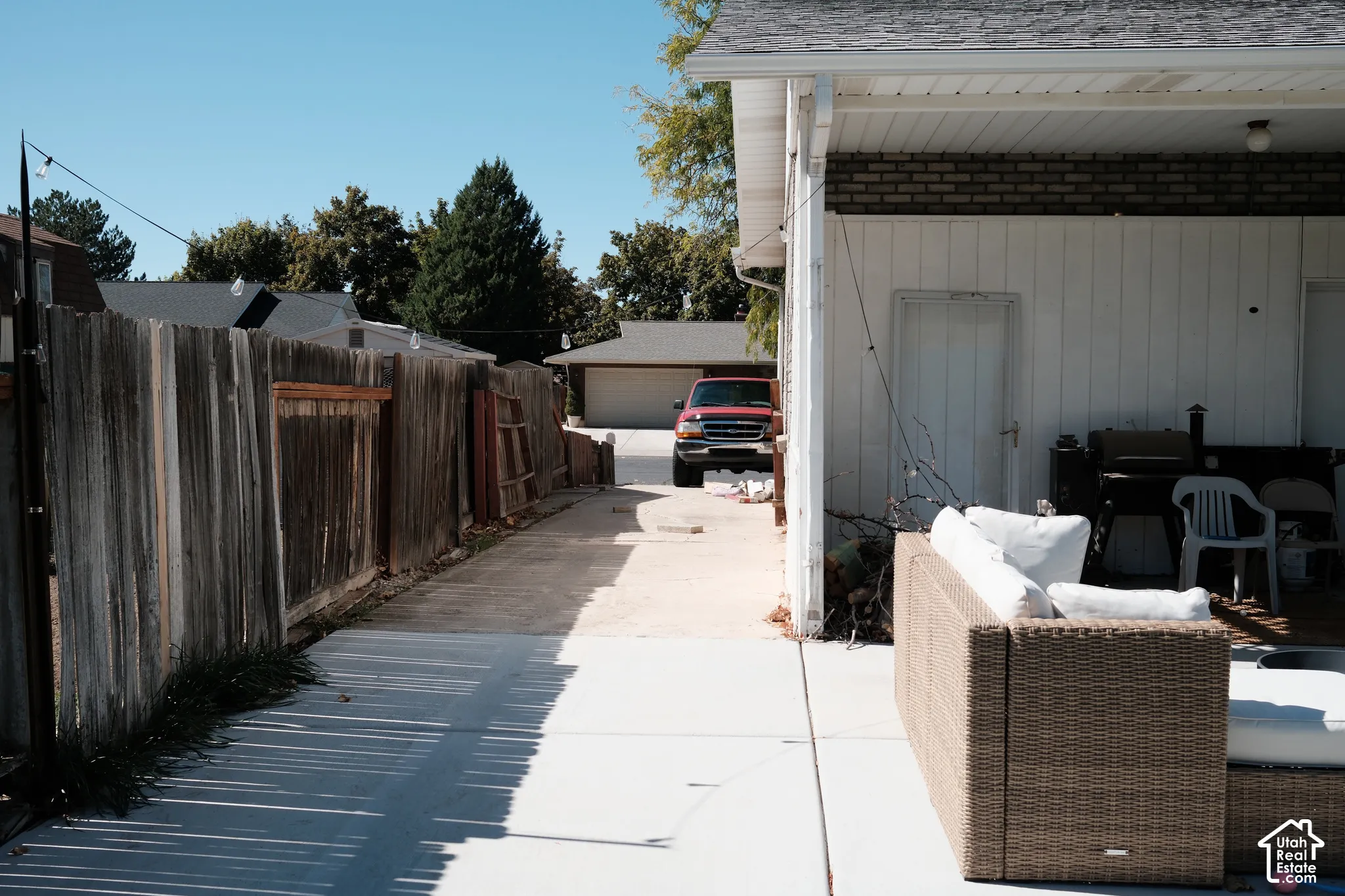 Concrete patio area featuring an attached covered porch and a wood privacy fence