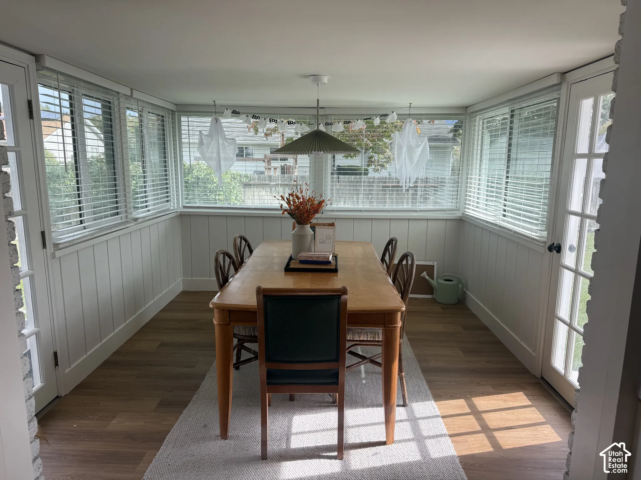 Sunroom featuring wood-finish flooring, vertical paneling, perimeter windows with blinds, and dual glass-panel exterior doors