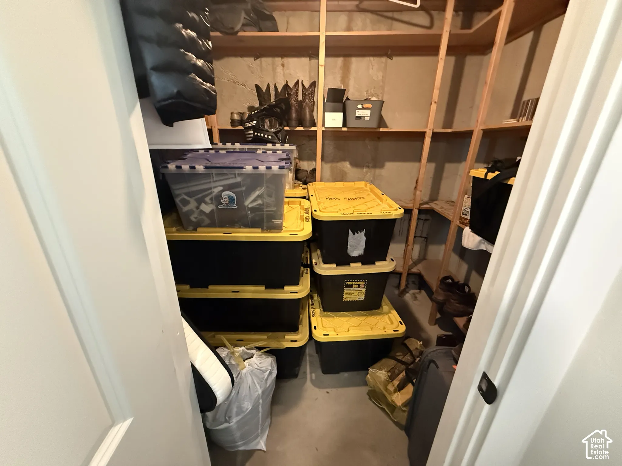 Storage space featuring multi-level wooden shelving and concrete walls