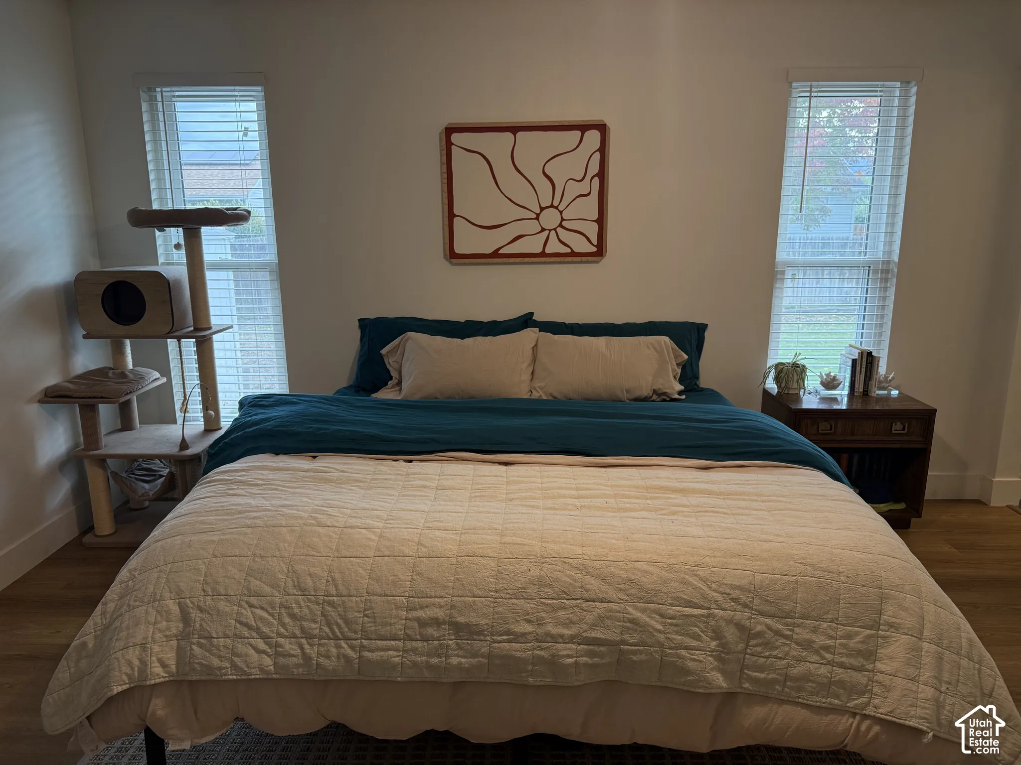 Neutral-toned room featuring wood-finish flooring and two windows with horizontal blinds