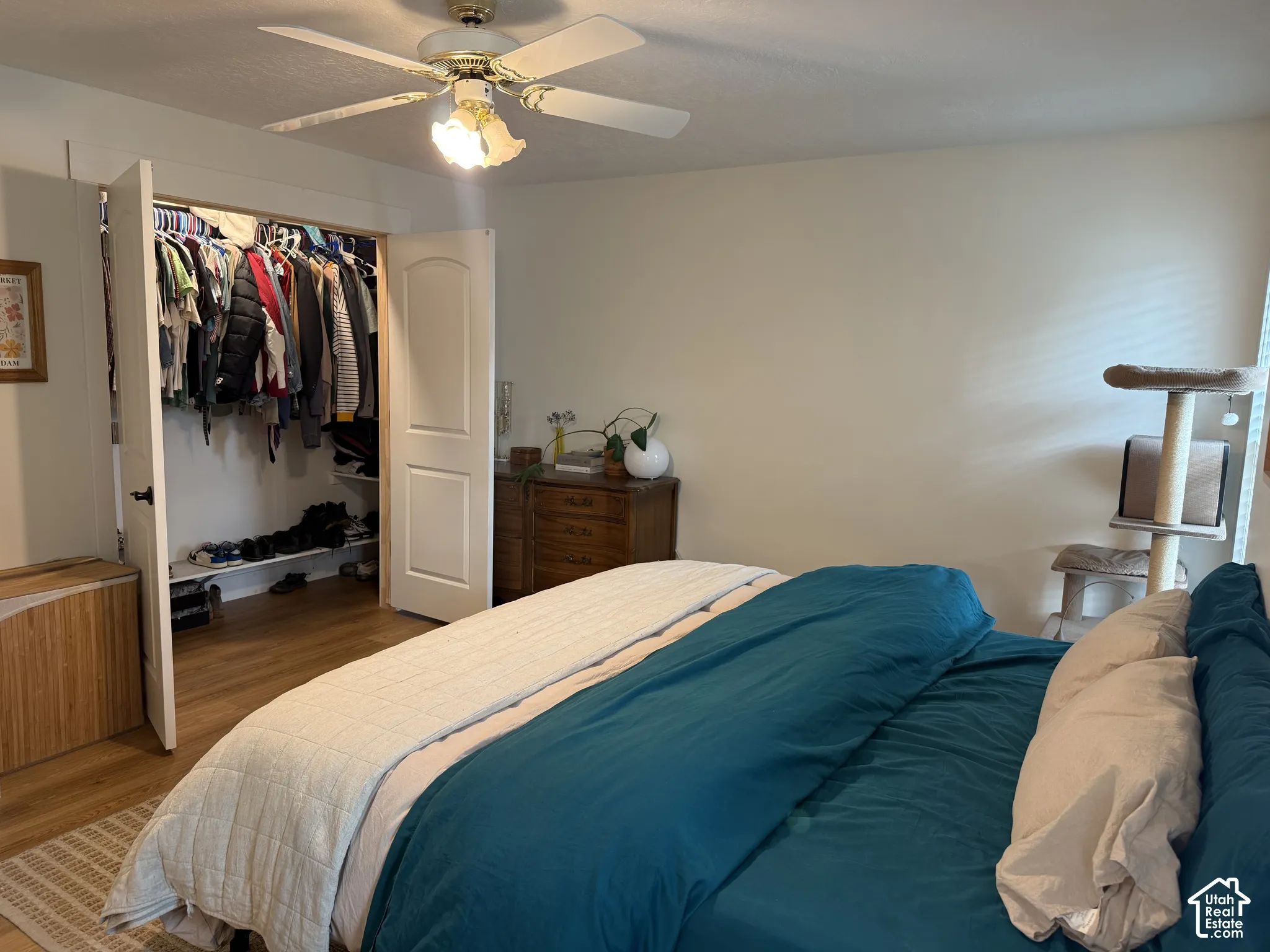 Bedroom featuring wood-finish flooring, a ceiling fan with integrated lighting, and a reach-in closet with double arched doors