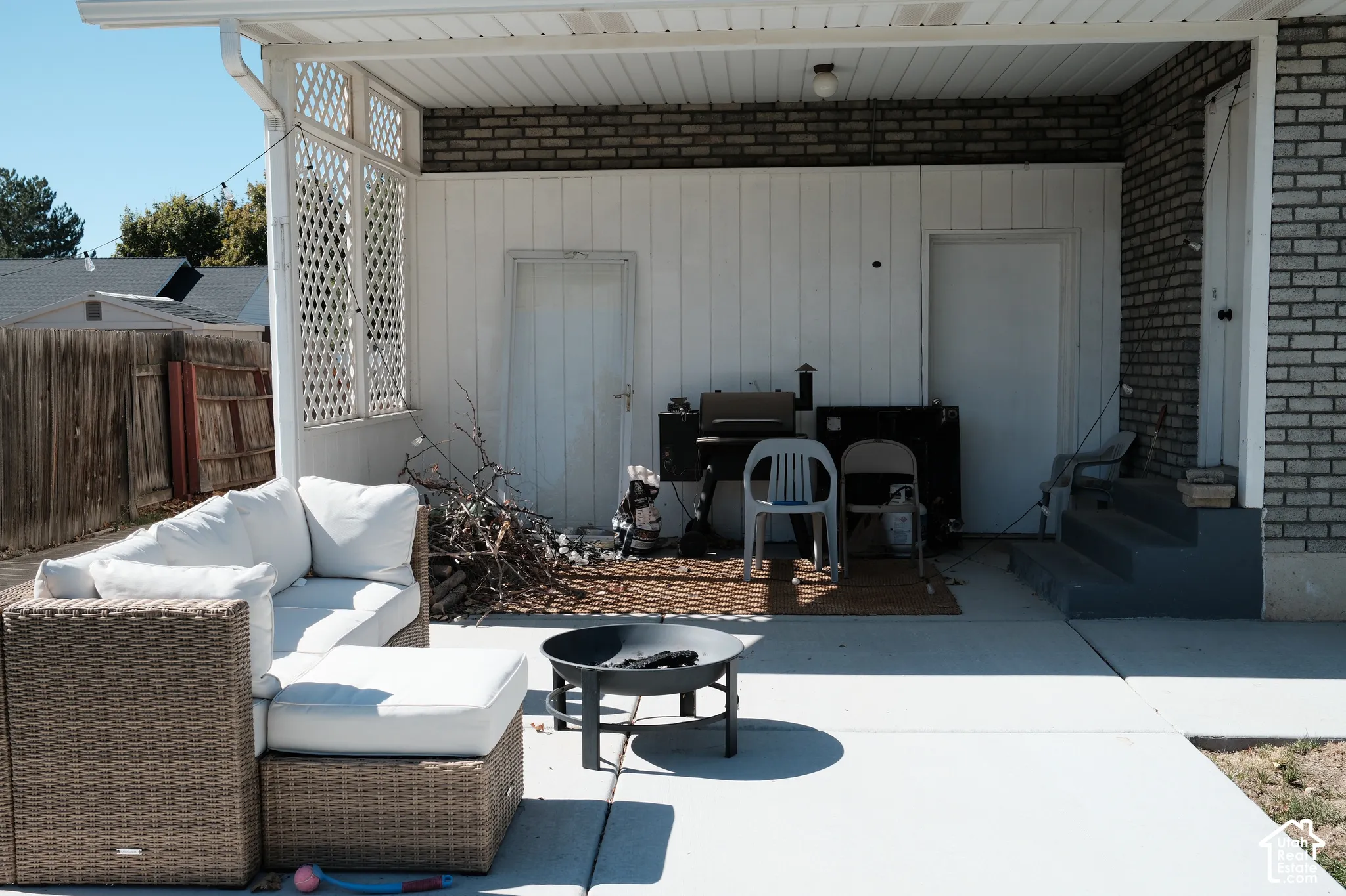 Covered patio featuring concrete flooring, lattice wall paneling, and masonry exterior walls