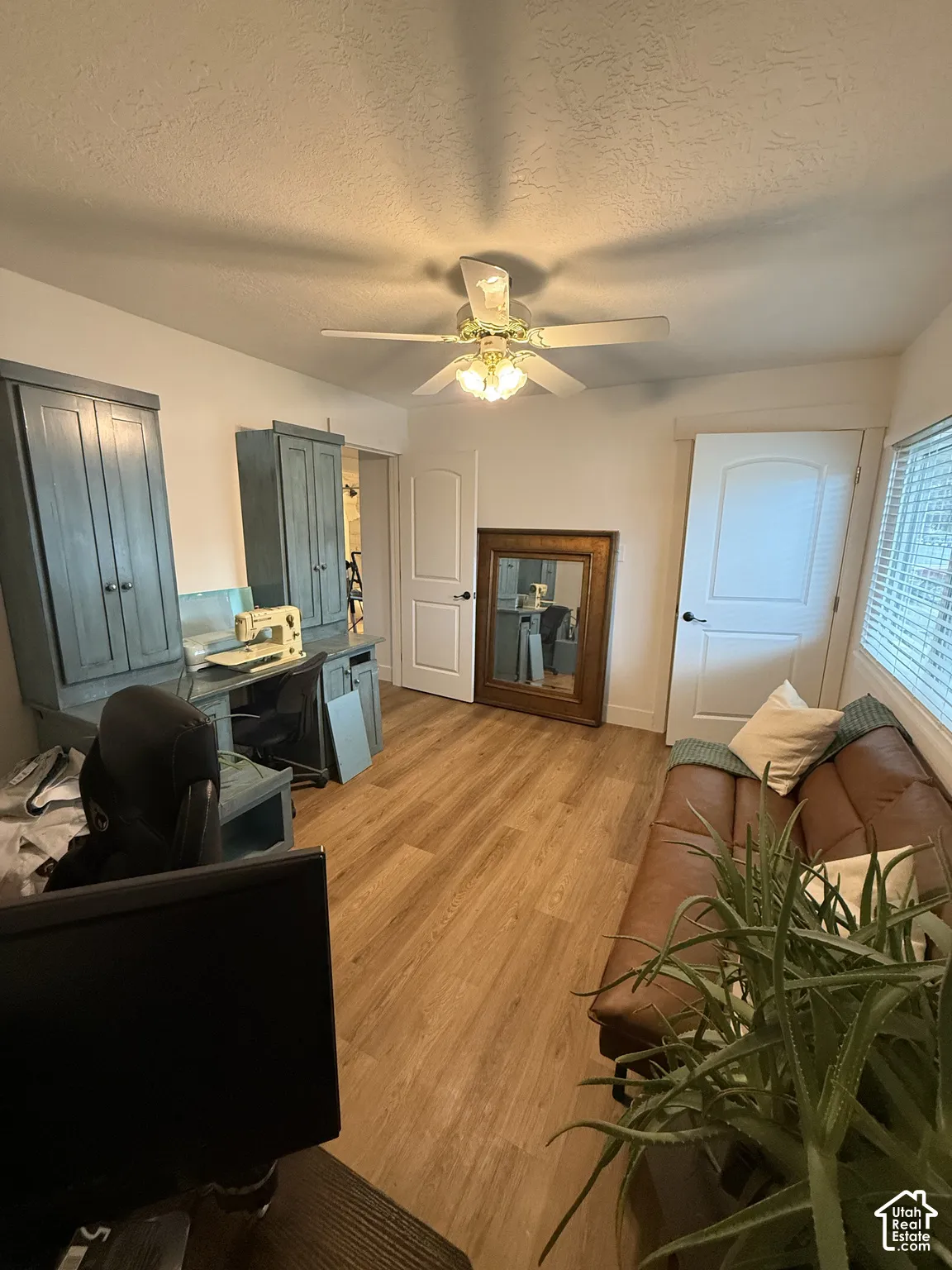 Room featuring wood-finish flooring, built-in cabinetry with desktop workspace, dual-panel interior doors, and a ceiling-mounted light fixture with a central fan