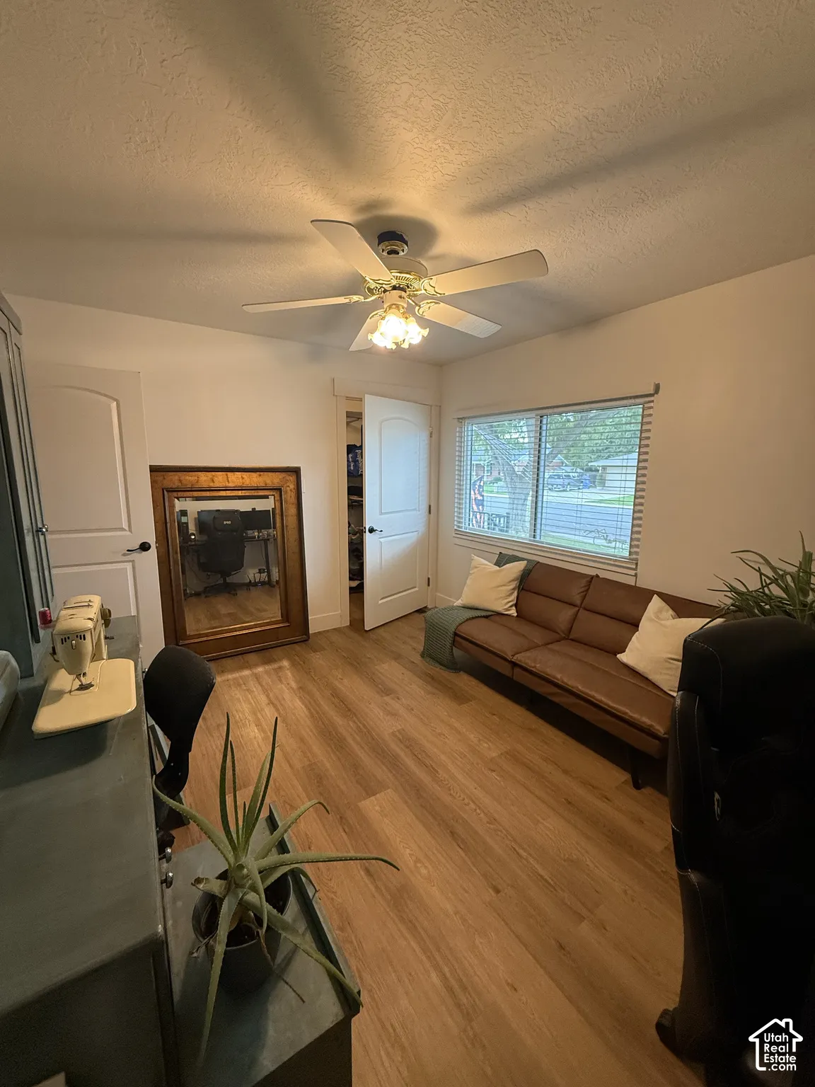 Room featuring wood-finish flooring, a ceiling fan with integrated light fixture, horizontal sliding window, and interior doors with matte black hardware