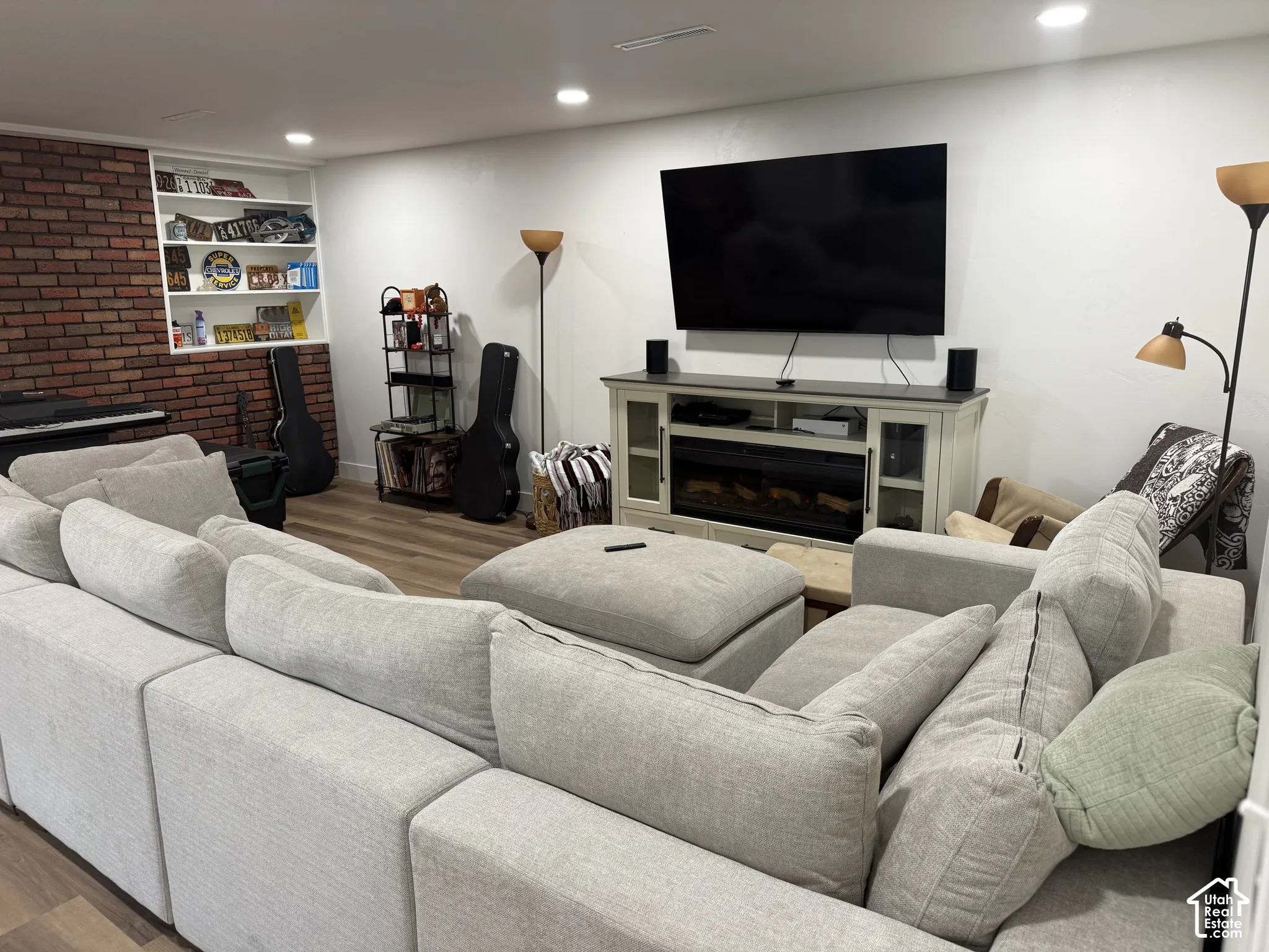 Interior space featuring wood-finish flooring, a decorative brick accent wall, recessed lighting, and built-in wall shelving